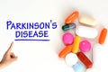 Top view of ParkinsonÃ¢â¬â¢s disease text on white background near colorful pharmaceutical drugs